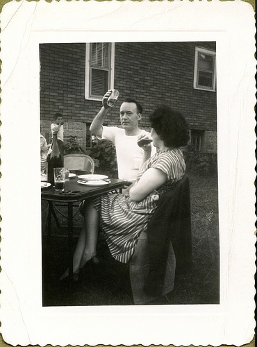 Vintage man raising beer for toast outside.