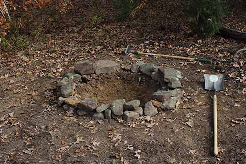 Digging fire pit for backyard campfire rocks around edges rim.