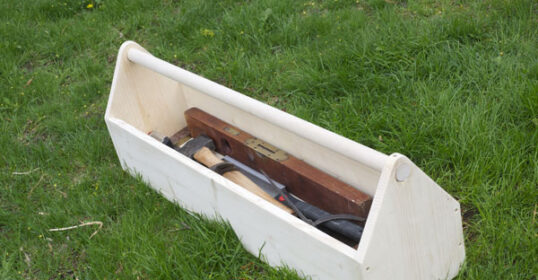 A wooden tool carrier sitting on the grass.
