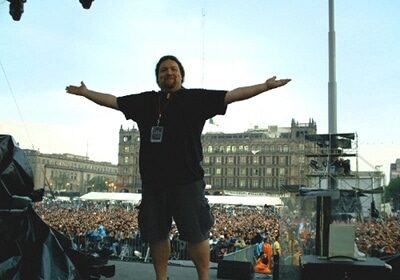 A video engineer standing on stage with his arms outstretched.