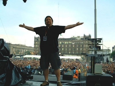 A video engineer standing on stage with his arms outstretched.