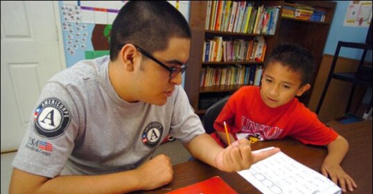 A man and a young boy sitting at a table discussing the benefits of taking a gap year.