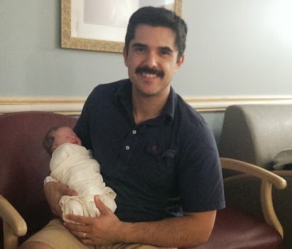 man dad with newborn baby girl swaddled