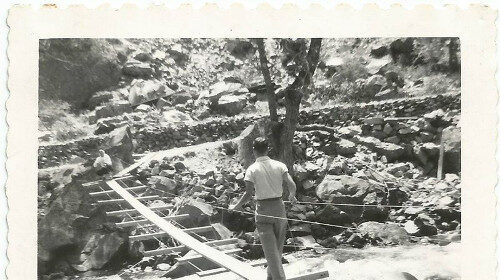 An old photo capturing a man crossing a rustic wooden bridge, reflecting Man's Chief Purpose and exuding a sense of Manvotional aura.