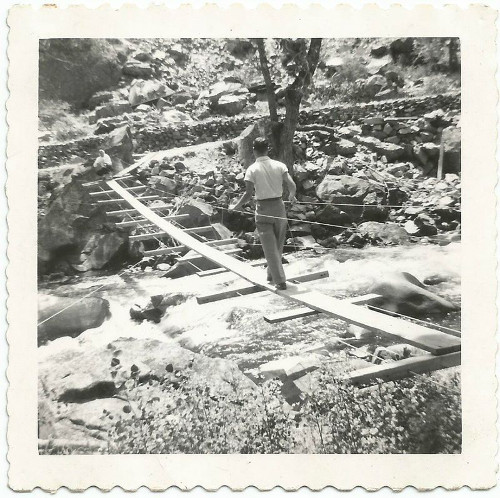 An old photo capturing a man crossing a rustic wooden bridge, reflecting Man's Chief Purpose and exuding a sense of Manvotional aura.