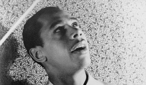 A hep black and white photo of Cab Calloway jiving on the floor.