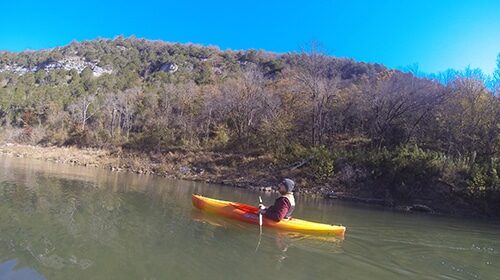 A person is paddling a kayak on a wild river.