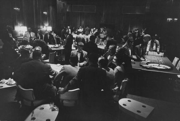 A black and white photo capturing a group of professional gamblers in a room.
