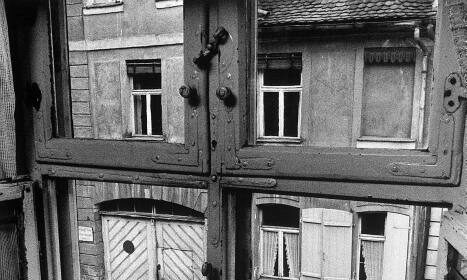 A fatherless boy looking out of a window at a car, pondering on the lessons he will learn as he grows into a man.