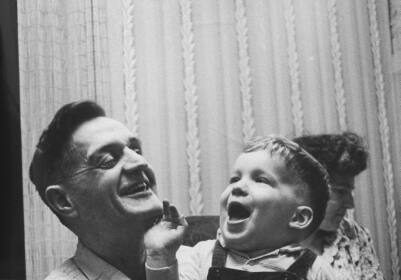 An old black and white photo of a man holding a child, depicting tenderness and care.