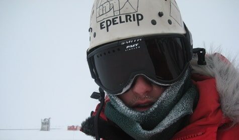 A Driller/Researcher wearing a helmet and goggles in the Antarctic snow.
