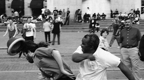 A man in a white shirt survives a street fight.