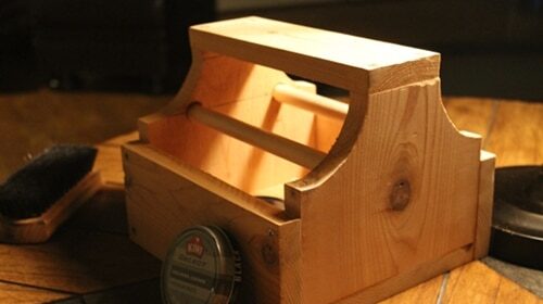 A shoe shine box on a table with a brush and a comb.
