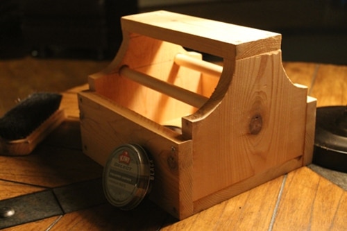 A shoe shine box on a table with a brush and a comb.