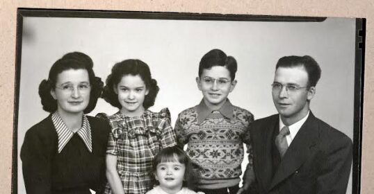 A black and white photo of a family, including grandparents, posing for a photo.
