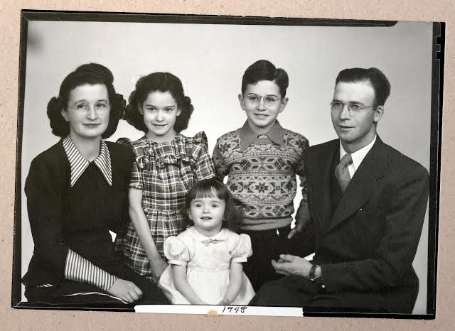 A black and white photo of a family, including grandparents, posing for a photo.