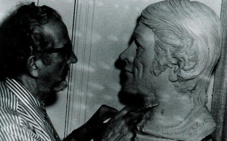 An old black and white photo of a man working on a modern bust.