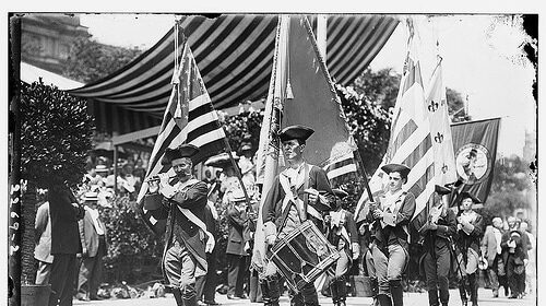 A group of men, symbolizing the nation's strength, proudly wave flags as they march in a parade.