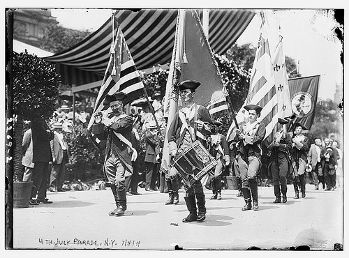 A group of men, symbolizing the nation's strength, proudly wave flags as they march in a parade.