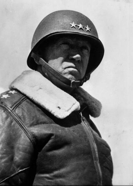 A black and white photo of a man wearing a George S. Patton helmet.