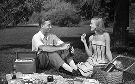 A perfect black and white photo of a man and woman having a picnic.