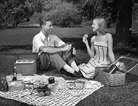 A perfect black and white photo of a man and woman having a picnic.