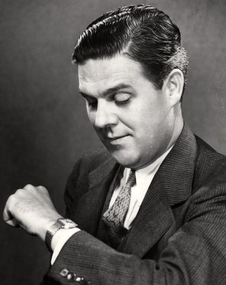 A punctual man in a suit looking at his watch.