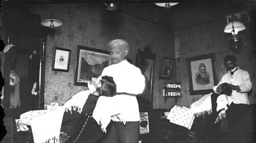 A man is getting a Straight Razor Shave in a barber shop.