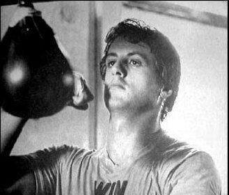 A black and white photo of a man punching a speed bag.