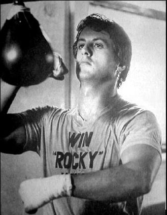 A black and white photo of a man punching a speed bag.
