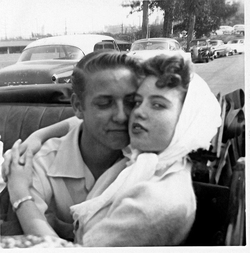 A man and woman dating, hugging in the back of a car.