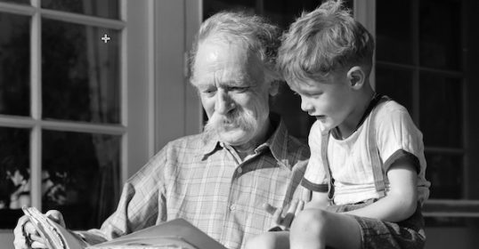 A grown man and a young boy appreciating a book.