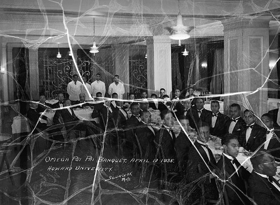 A black and white photo capturing a group of people engaged in a shared ritual, exuding an aura of power within the room.