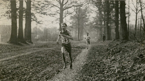 Two men prevent running injuries as they sprint down a path in the woods.