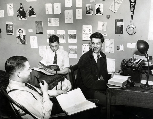 Three men testing out a moneyball strategy at a desk with a typewriter in front of them.