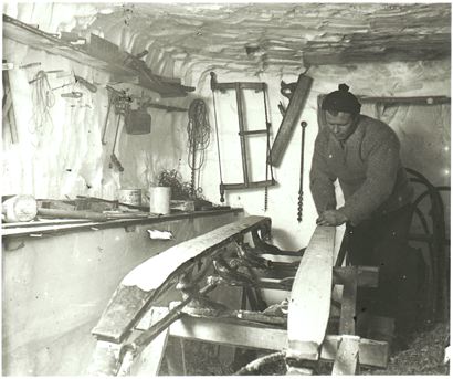 Vintage man waxing wooden skis.