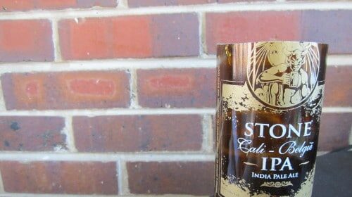 A bottle sitting on a table next to a brick wall.