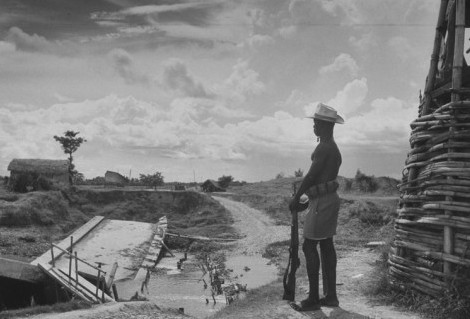 Vintage man guarding temple with rifle.