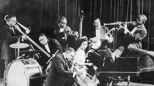 A black and white photo of a group of people playing instruments in a jazz appreciation scene.