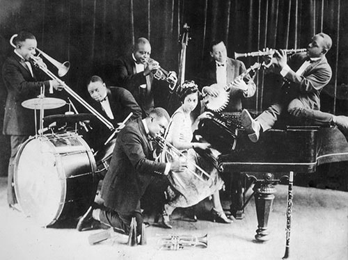 A black and white photo of a group of people playing instruments in a jazz appreciation scene.
