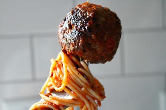 A person is holding a delicious meatball on a fork.