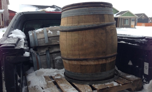 Old whiskey barrel in bed of pickup truck.