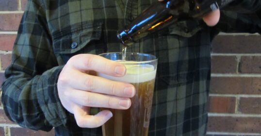 A man pour a beer into a glass.
