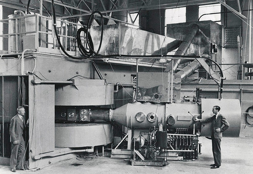 Vintage men in laboratory warehouse working on large machine.