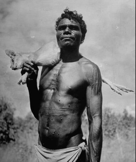 Vintage african man hunter with dead animal over shoulder.