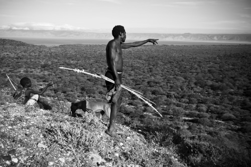 Young boy standing with spear hunting gear and a dog..