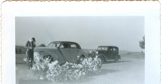 A grief-stricken friend seeks help alongside an old photo of two men standing next to a car.