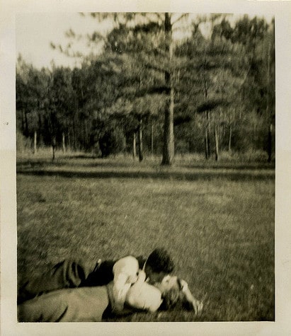 Vintage couple man woman kissing in outdoor field.
