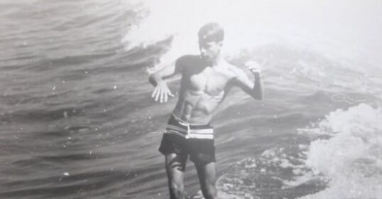 A man is riding a wave on a surfboard, embracing the thrill of living life to the limits as he Hack Your Flow.