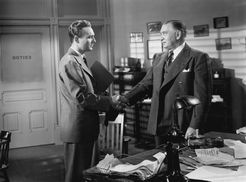 Vintage businessmen in suits shaking hands in office.